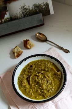 a bowl filled with green soup on top of a table