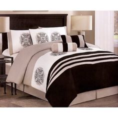 a bed with black and white comforters on top of it, next to a night stand