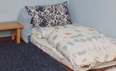 an unmade bed sitting on top of a wooden floor next to a blue wall