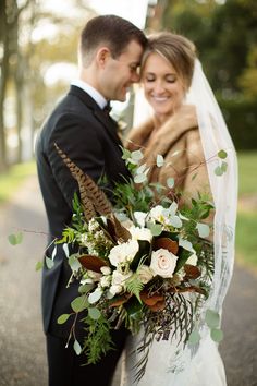 a bride and groom are standing together on the road with their bouquet in front of them