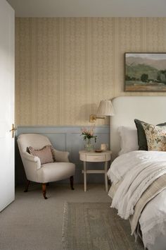 a white bed sitting next to a chair in a bedroom