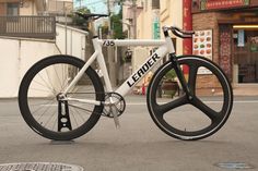 a white bicycle with black spokes parked on the street