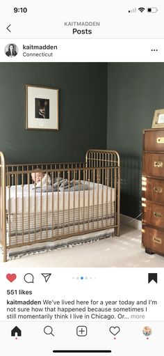 a baby in a crib next to a dresser with a framed photograph on the wall