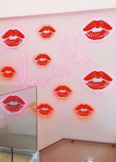 the neon sign has red lips on it and is next to a mirror that says love