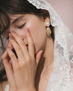 a woman wearing a veil and holding her hands to her face