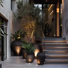 three large planters sitting next to each other on the side of a building with stairs leading up to it