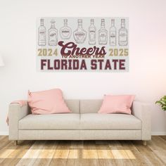 a couch with pink pillows in front of a white wall that says cheers to another year florida state