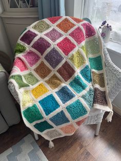 a crocheted blanket sitting on top of a wooden floor next to a window