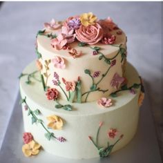 two tiered cake decorated with flowers and leaves