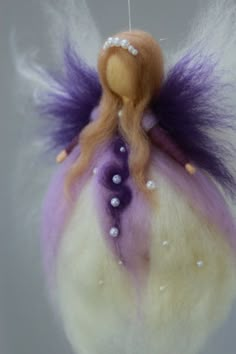 a needle - felt doll with purple hair and pearls hanging from it's back