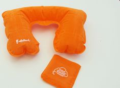 an orange travel pillow with two pillows on the top and one in the middle, sitting next to it