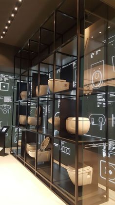 a glass display case filled with lots of bowls and plates on top of black shelves