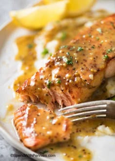 a piece of salmon covered in gravy on top of mashed potatoes