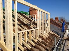 a house being built with wooden framing on top of the roof and wood slats