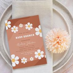 a baby shower is shown on a plate with a flower in front of the card