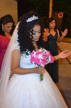 a woman in a wedding dress holding a bouquet and wearing a tiara with her hands out