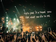 a group of people holding up their cell phones in front of a stage with the words, this one is a thank you for what you did to me