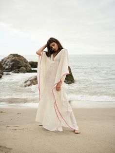 A semi-sheer maxi caftan made from eco-friendly jamdani cotton fabric handspun by weavers of India. It is detailed with delicate woven motifs and pink selvedge, V-shaped neckline, wide kimono-inspired sleeves and side slits. This quintessential beach or poolside cover-up is long, flowy and made with sustainable materials. Sustainable Materials, V Shape, Cover Up, Cotton Fabric, Eco Friendly, India, Fabric, Pink