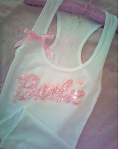 a baby bib with pink sequins and a bow on the front is laying on a bed