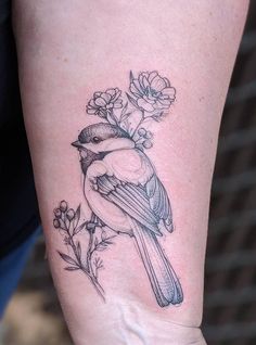 a small bird with flowers on it's arm