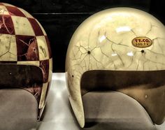 two pieces of art that look like helmets with cracked paint on them, sitting next to each other