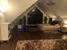 an attic bedroom with hardwood floors and white furniture