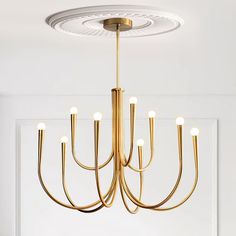 a gold chandelier hanging from the ceiling in a room with white walls and flooring