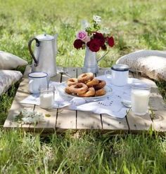 a table topped with doughnuts and milk on top of a grass covered field