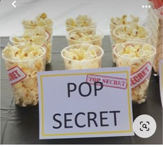 there are many cups with popcorn in them on the table next to a sign that says pop secret