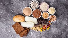 several bowls filled with different types of food on top of a cement floor next to bread and other foods