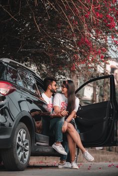 a man and woman sitting on the back of a car