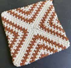 an orange and white crocheted dishcloth on a black surface