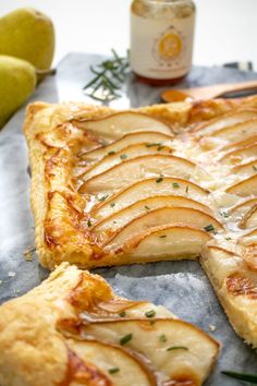 an apple tart with slices cut out on a table next to some pears