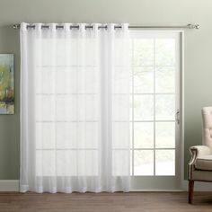 a living room with white curtains and a chair