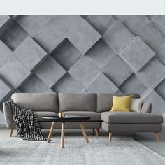 a couch and table in front of a grey wall with geometric tiles on the walls