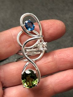 I've created this Bohemian abstract large finger ring, a true statement piece, in sterling silver, which features a 10x8mm oval Peridot, a 6mm White Topaz and an 8x6mm Blue Zircon. I make everything in 925 Sterling Silver and can Rhodium plate if you wish over the piece. I use AA+ grade gemstones in my work. The ring base is 12 gauge round sterling silver wire. No two are alike has I hand-fabricate one-of-a-kind designs. This statement ring is sturdy and I soldered many contact points and harden Chic Rings, Artisan Rings, 12 Gauge, Bohemian Rings, Blue Zircon, Finger Ring, Moon Pendant, White Topaz, Silver Wire