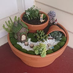 there is a potted planter with plants in it and small figurines on the ground