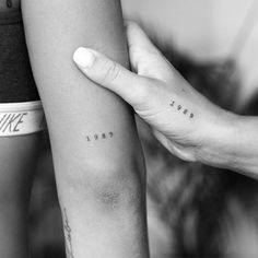 two people with matching tattoos on their arms holding each other's arm and the word love is written in small cursive letters