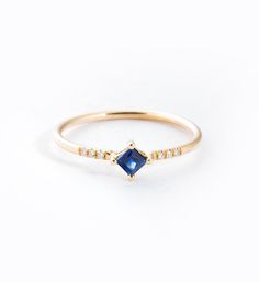 Try looking at a square cut gemstone in a new way—literally. This stunning blue sapphire comes in a classic square cut, but is rotated to give it an arresting new look. Four prongs at each corner complete the setting for a beautiful mix of new taste and classic technique. The polished 14 karat yellow gold band is finished with a pave of three 1 point white diamonds on each side, their pure white brilliance making for a lovely contrast against the sapphire's deep, rich color. We think this band i Sapphire Ring Simple, Rings Sapphire, Gold Leaf Rings, Aesthetic Rings, Future Engagement Rings, Rings Rings, Sapphire Engagement Ring Blue, Gold And Silver Rings, Birthday Ring