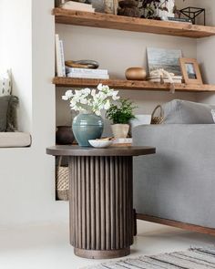 a living room filled with furniture next to a gray couch and white flowers on top of a table