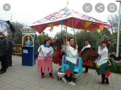 several people dressed in costumes standing under an umbrella