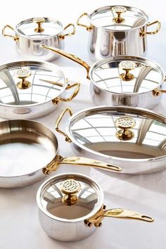 several pots and pans with gold handles on a table