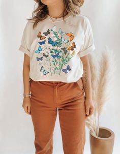 The Butterflies! Flowers! So gorgeous all together across this t-shirt with a vintage feel. The t-shirt is unisex sizing, made to be inclusive for both men and women. C O L O R S ✺ Natural I N K ✺ Eco-friendly, water-based, bio-degradable, non-toxic M A T E R I A L ✺ 100% cotton ✺ Preshrunk F I T + S I Z I N G ✺ UNISEX t-shirt ✺ Please review the size chart in the photos for measurements I M P O R T A N T ✺ Processing time to make your item is typically 1-7 business days. ✺ If you need to CANCEL Botanical Tshirt, Alt Aesthetic, Indie Clothing, Mom Graphic Tees, Butterfly Shirt, Mori Kei, Butterflies Flowers, Halloween Graphic Tees, Halloween Graphic