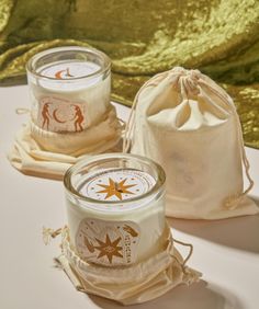 two candles sitting on top of a table next to a drawstring bag and gold sequins