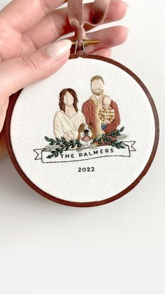 a hand holding a small embroidered ornament with the image of two people on it