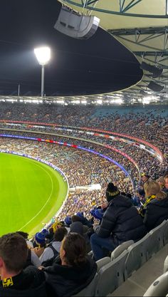 a large stadium filled with lots of people sitting on the bleachers at night