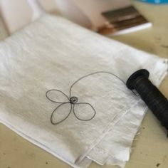 a piece of cloth with a black thread on it sitting next to a sewing needle