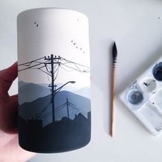 a hand holding a coffee mug with an image of power lines and telephone poles on it