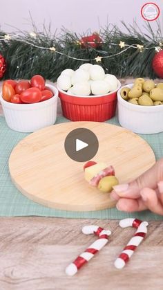 a person is cutting up food on a board with candy canes in front of them