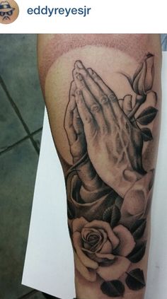 a black and white photo of a person's arm with a praying hands tattoo on it